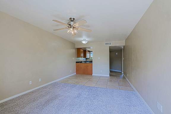 A spacious room with a ceiling fan and a carpeted floor.