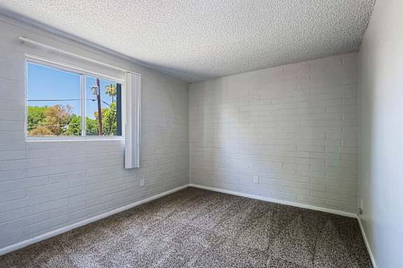 A room with a window and a white brick wall.