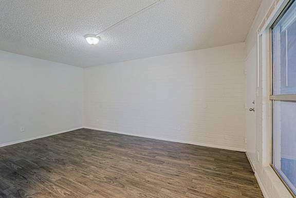 A room with wooden flooring and a window on the right side.