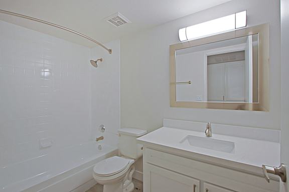 A white bathroom with a toilet, sink and mirror.