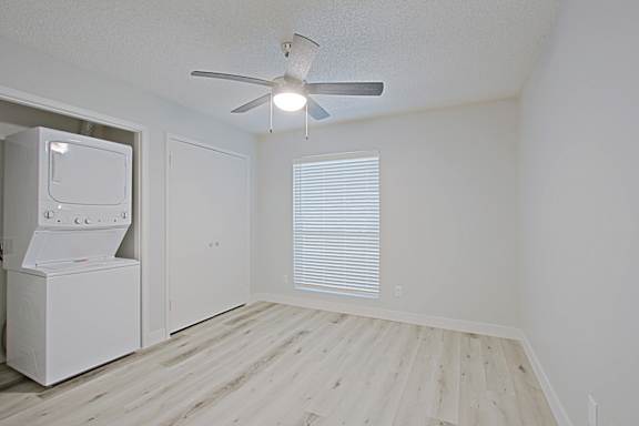 A white room with a fan and a washing machine.