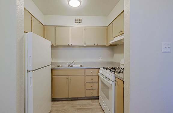 A kitchen with a white refrigerator, a white stove, and a sink with a countertop.