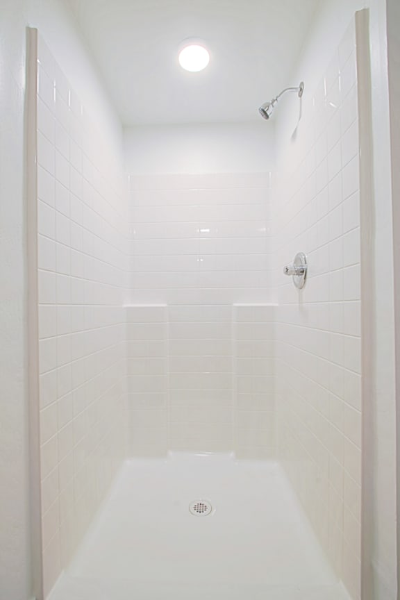 a white tiled shower in a bathroom with a shower head a white tiled shower in a bathroom with a shower head at 2051 Apartments, Prescott, AZ