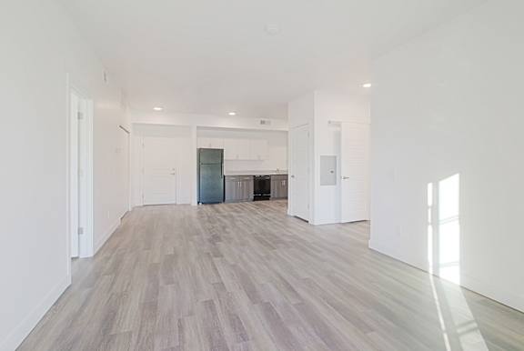 an empty living room and kitchen with white walls and wood flooring an empty living room and kitchen with white walls and wood flooring at 2051 Apartments, Arizona, 86301