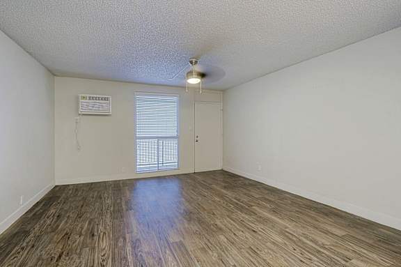 A room with wooden flooring and a window with blinds.