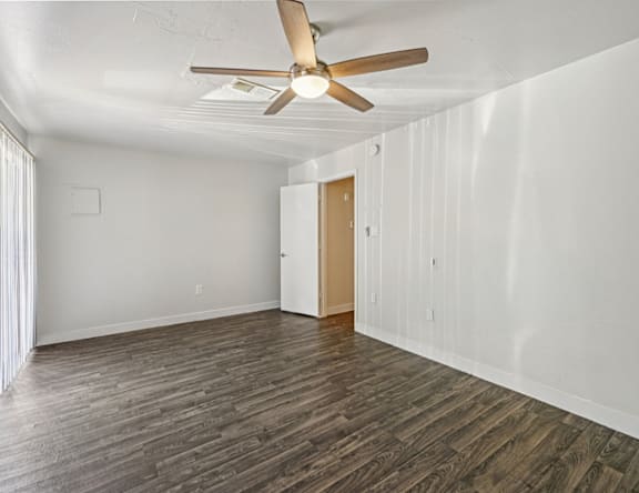 A room with a ceiling fan and wooden flooring.