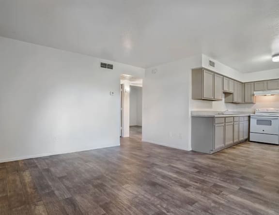 A kitchen with white cabinets and a wooden floor.