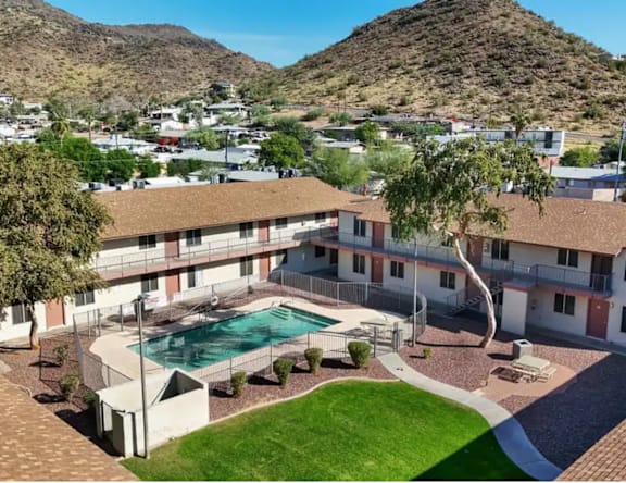 A large apartment complex with a pool and a mountain in the background.