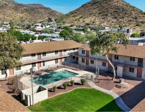 A pool is surrounded by a grassy area and a building.