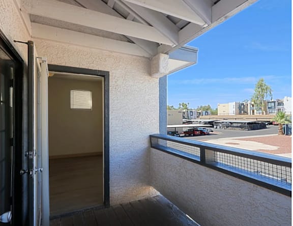 A balcony with a view of a parking lot and buildings.