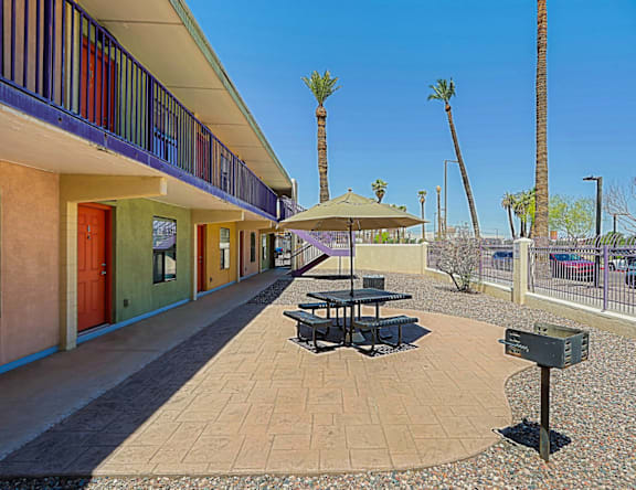 A sunny day at a colorful building with a patio and palm trees.