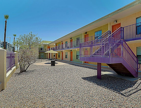 A building with a purple staircase and a gravel courtyard.