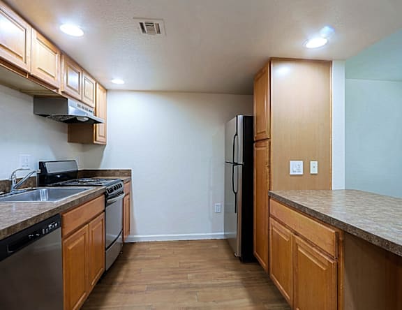 A kitchen with wooden cabinets and a black refrigerator.