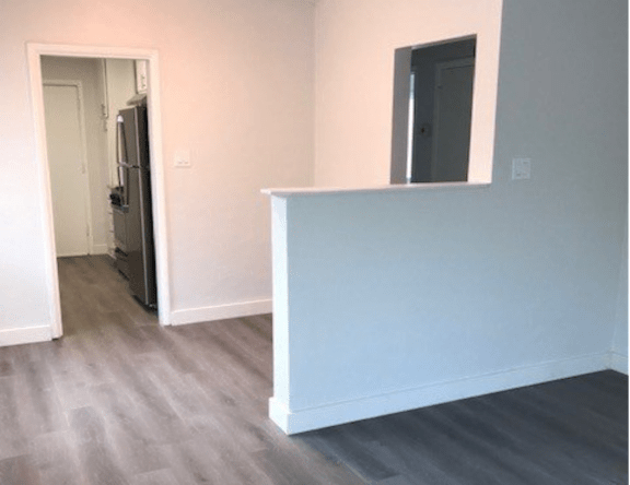 A white wall with a small window and a doorway leading to another room.