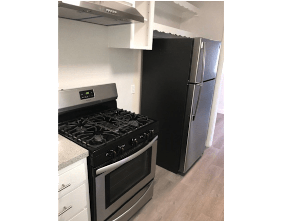 A black stove and refrigerator in a kitchen.