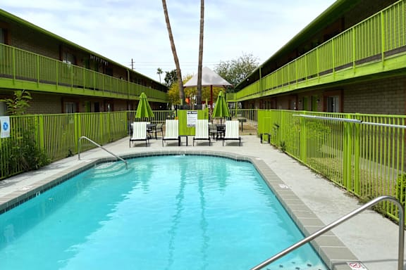 A small pool surrounded by a green fence and a metal railing.