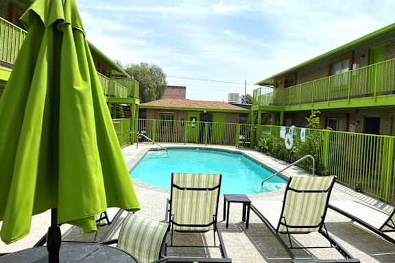 A green umbrella is next to a pool.