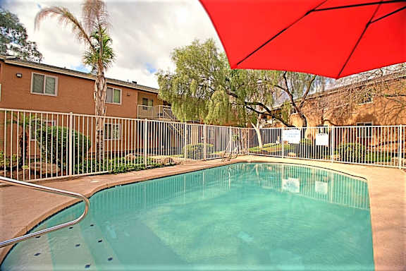 A red umbrella is over a pool.