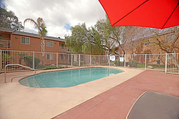 A red umbrella is covering a pool area.