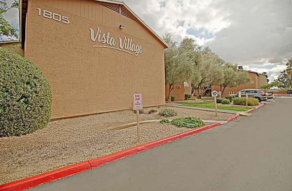 A street view of Vista Village with a red curb and a no parking sign.