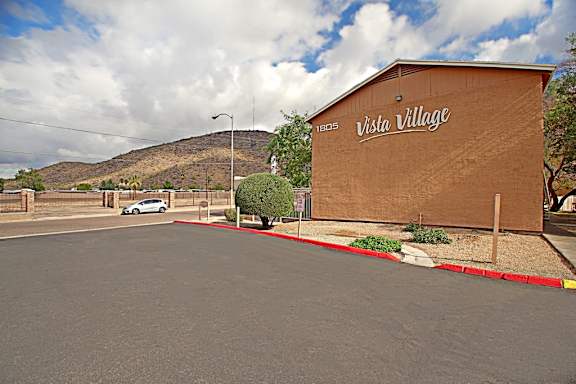A street view of Vista Village with a car parked in front of the building.