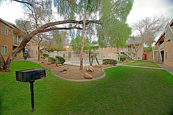 A mailbox sits on a lawn in front of apartment buildings.