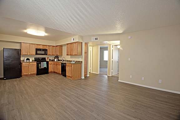 A kitchen with wooden floors and a black refrigerator.