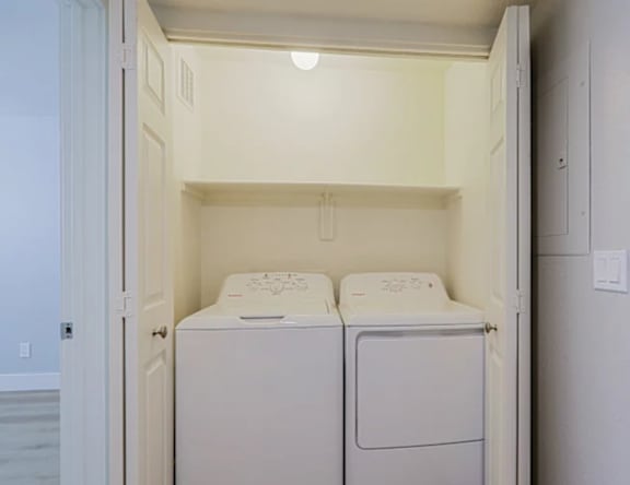 Two white washing machines in a small laundry room.