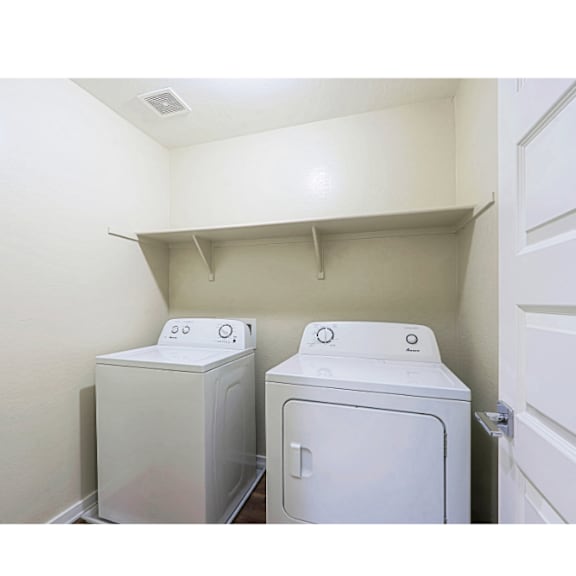 Two white front loading washing machines in a small laundry room.