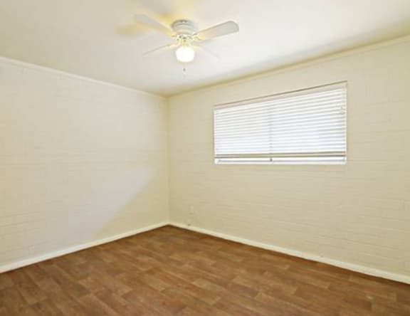 A room with a ceiling fan and a window with blinds.