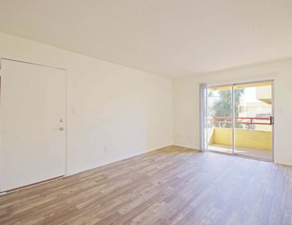 A room with a white door and a window with a view of a balcony.