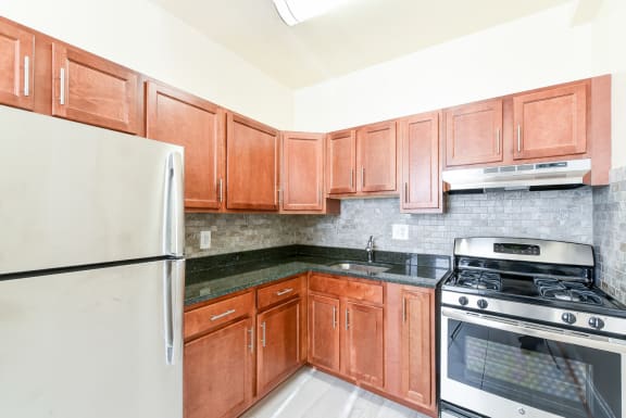 kitchen with wood cabinetry, stainless steel appliances and tile backsplash at the norwood apartments in adams morgan washington dc
