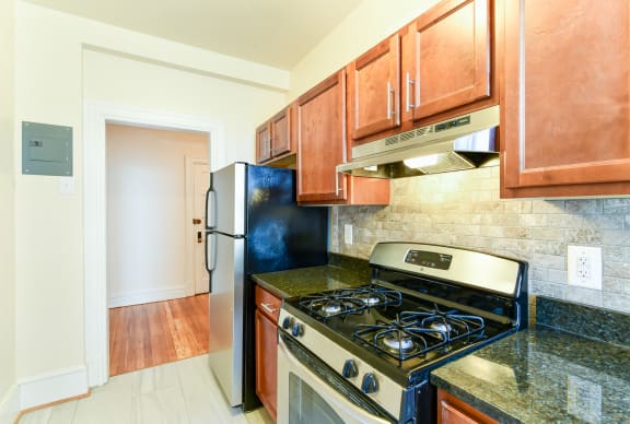 kitchen with oak cabinetry, tile flooring and stainless steel appliances at 2701 connecticut apartments in washington dc