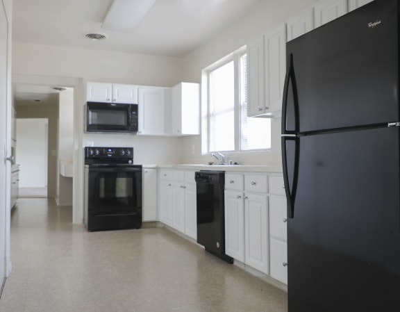 a kitchen with white cabinets and black appliances at Ingram Manor Apartments, Pikesville, Maryland