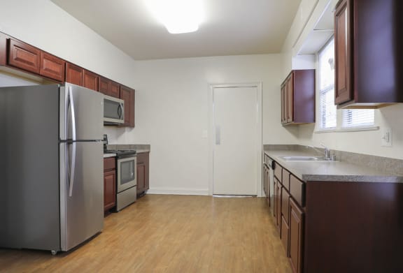 a kitchen with wood floors and brown cabinets  at Ingram Manor Apartments, Pikesville, MD