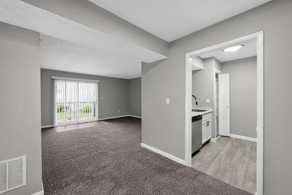 A spacious room with a kitchenette and a window with blinds.