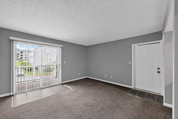 A room with a white door and a window with a view of a street.
