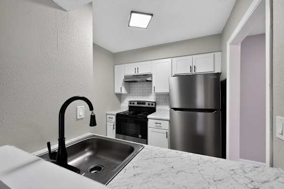 A kitchen with a sink, stove, and refrigerator.