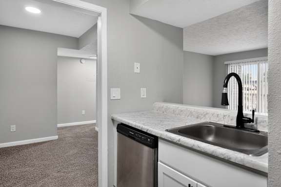 A kitchen with a sink and a trash can.