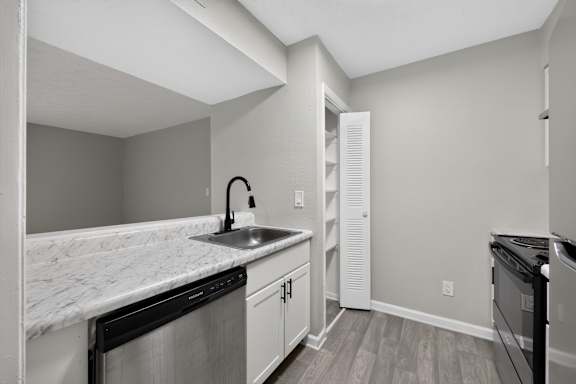 A kitchen with a marble countertop and white cabinets.