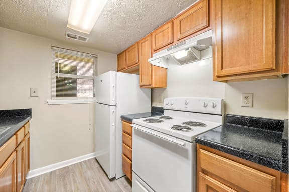 a kitchen with white appliances and wooden cabinets at Bradford Gwinnett Apartments, Norcross, 30071