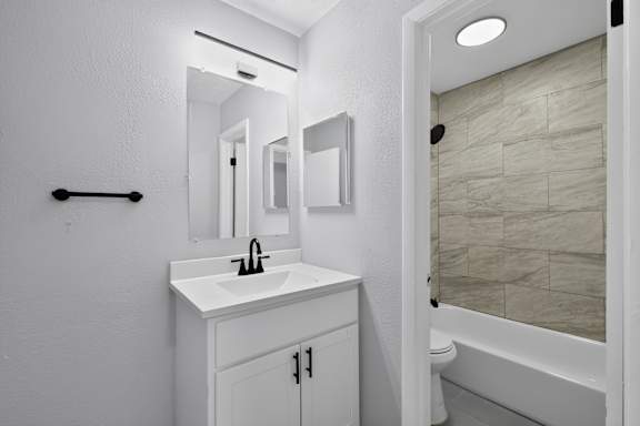 A white bathroom with a sink, mirror, and bathtub.