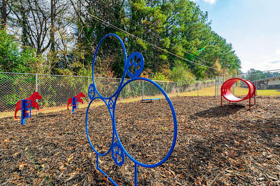 A playground with a blue metal structure and red chairs.