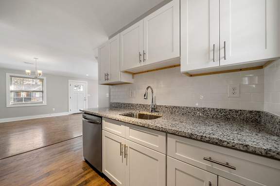 A kitchen with white cabinets and a granite countertop with sink  at Balfour Marietta Apartments, Marietta, GA