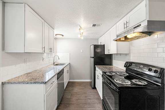 A kitchen with black appliances and white cabinets.