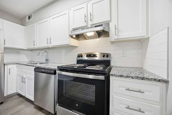 A modern kitchen with a black stove top oven and white cabinets.