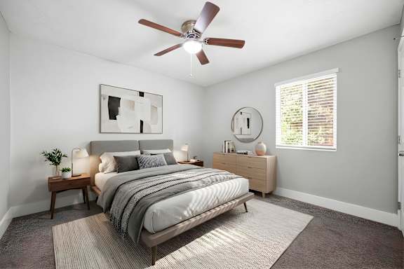 A bedroom with a bed, nightstand, and a ceiling fan.