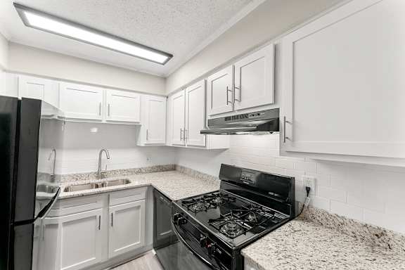 A kitchen with a black stove top oven and white cabinets.