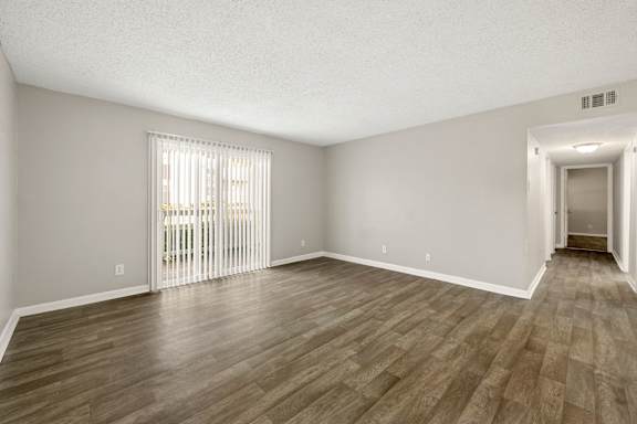 A room with wooden flooring and a sliding glass door.