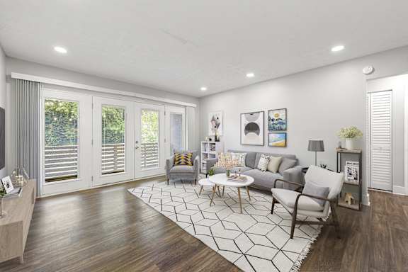 A modern living room with a grey sofa, a coffee table, and a large window with blinds.